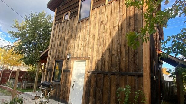 Ein rustikales Holzhaus mit Haustür, Fenstern und einer Holzterrasse.