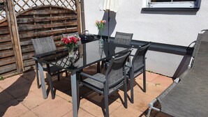 An outdoor patio with a glass table, four chairs, and a vase with flowers. - Comfortable, very quiet and sunny apartment. Only 5 minutes to the Silbersee (Villach)