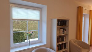 A room with a large window, a bookshelf, and a chair. - Comfortable, very quiet and sunny apartment. Only 5 minutes to the Silbersee (Villach)