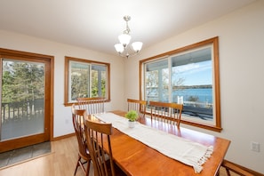 Enjoy meals in this dining area with a table for four, surrounded by large windows offering views of a body of water.