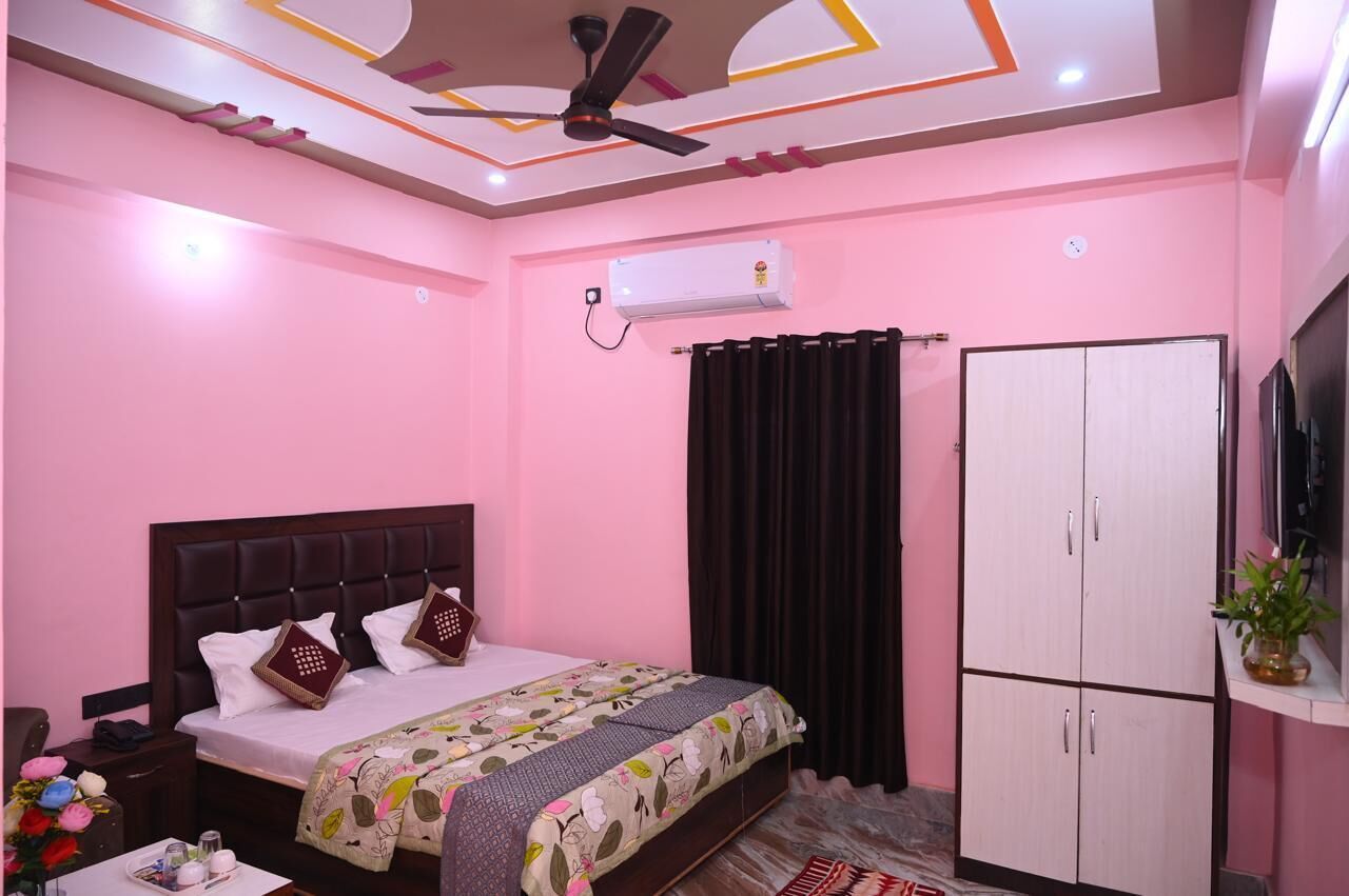 Un dormitorio con cama, armario, ventilador de techo, aire acondicionado y una pequeña mesa con un florero.