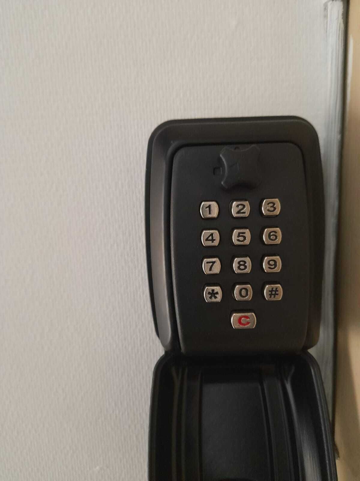 A black telephone with a numeric keypad and a red "C" button, placed against a white wall.
