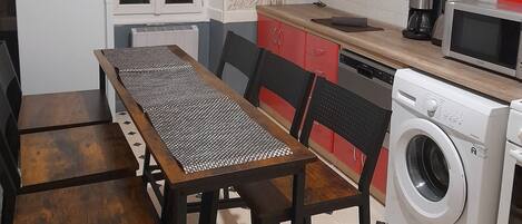 A compact kitchen with a dining area, a washing machine, and a microwave.