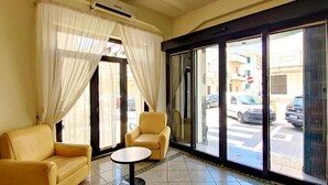 Um saguão de hotel com sofá, poltrona e mesa redonda.