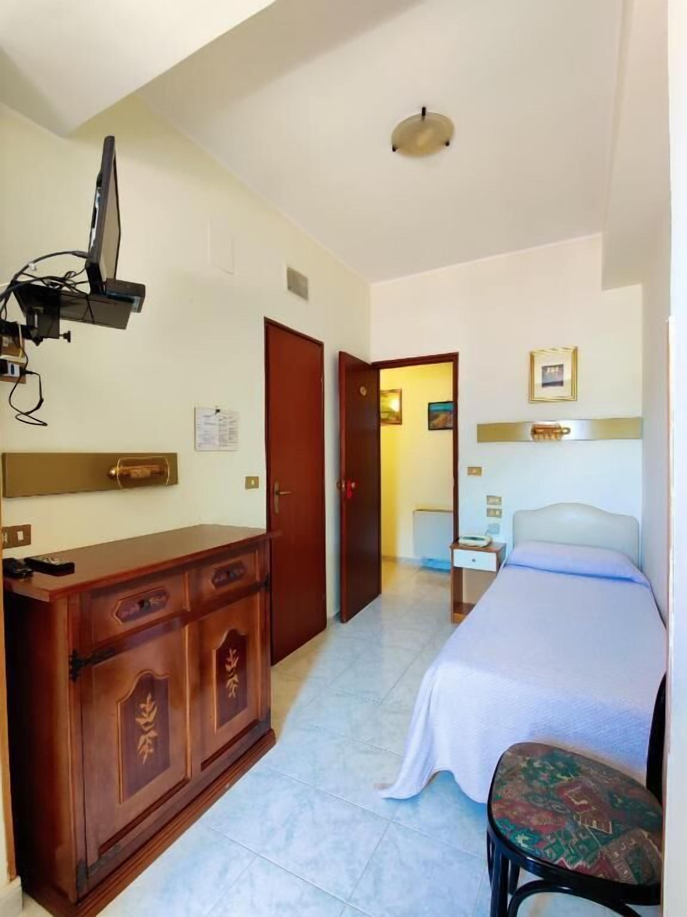 Une chambre d’hôtel équipée d’un lit, d’un bureau, d’une chaise et d’un téléviseur fixé au mur.