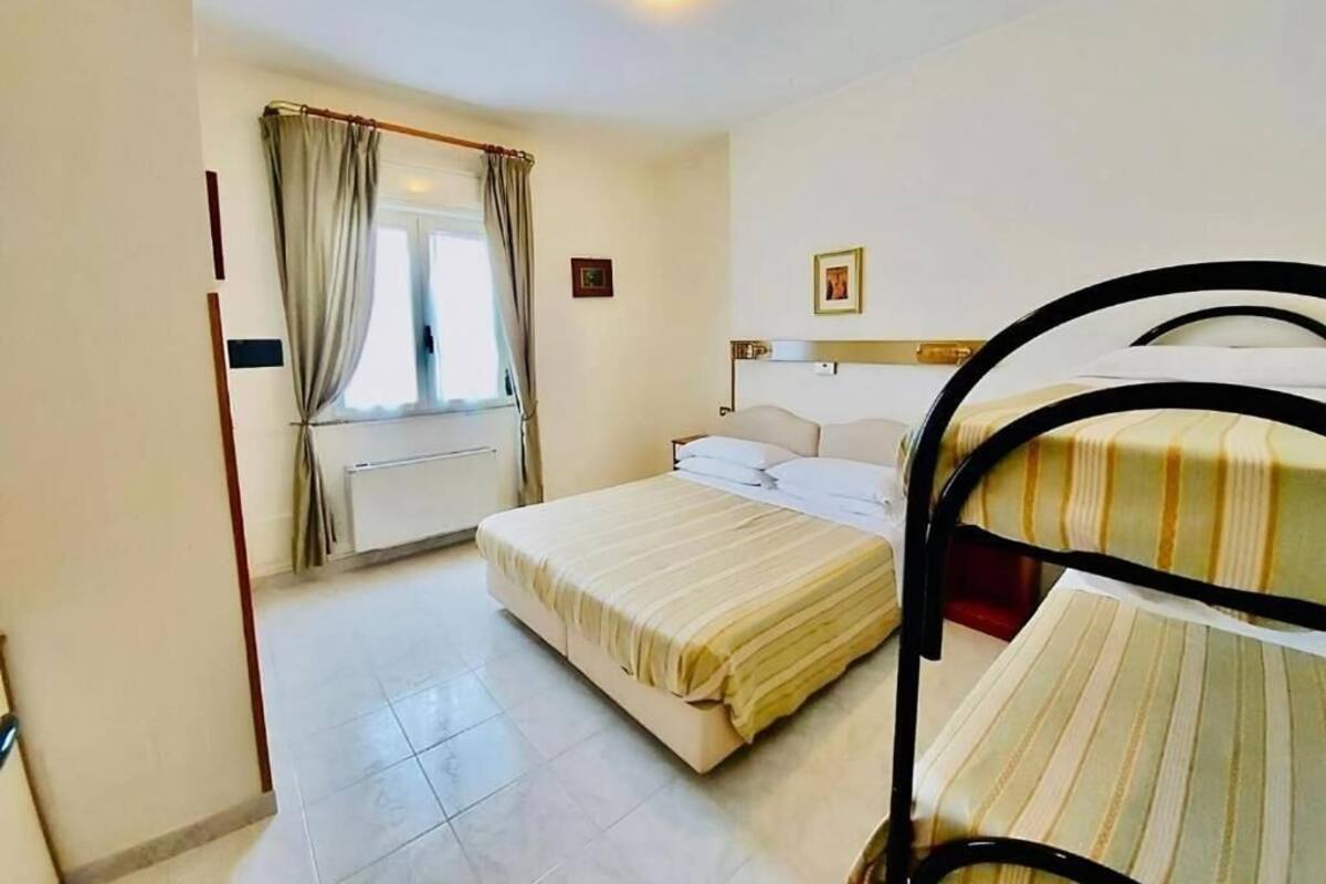 A bedroom with a bed, a window with curtains, a radiator, and a headboard.