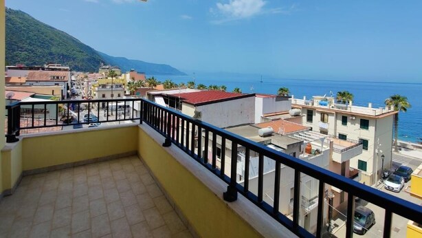 Uma varanda com vista para uma cidade costeira, edifícios e uma montanha ao longe.