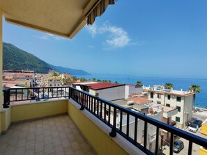 A balcony with a view of a coastal town, buildings, and a mountain in the distance. - Albergo delle Rose (Bagnara Calabra)