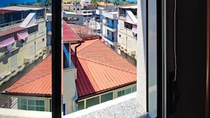 Vista da janela para uma cidade costeira com edifícios e um céu azul límpido.