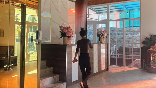 A hotel lobby with a wooden ceiling, marble walls, and a reception desk with floral arrangements. - Triland Hillside (Phu Quoc)