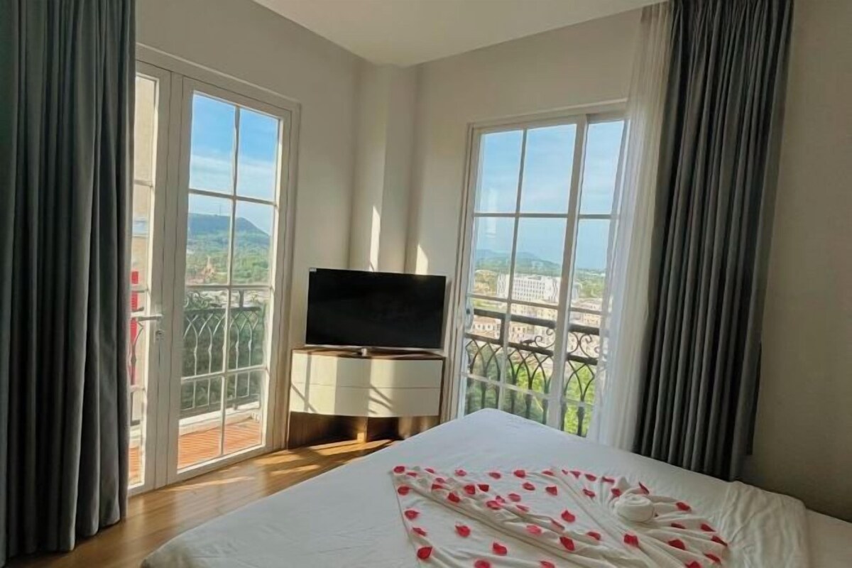 Een hotelkamer met een bed, een televisie en een balkon met uitzicht.