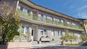 Ein zweistöckiges Wohnhaus mit Balkon, Fenstern und Topfpflanzen.