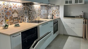 Ett modernt kök med ljusblå skåp, ett mönstrat stänkskydd och rostfria vitvaror.