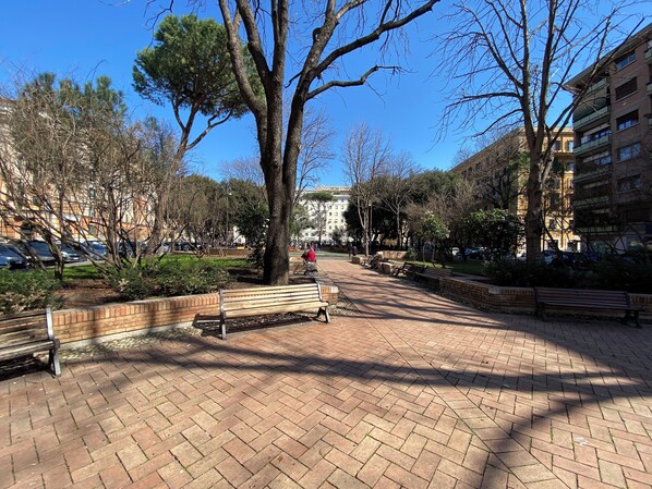 A paved walkway with benches, trees, and a building in the background. - Alice's apartment 1 (Roma)