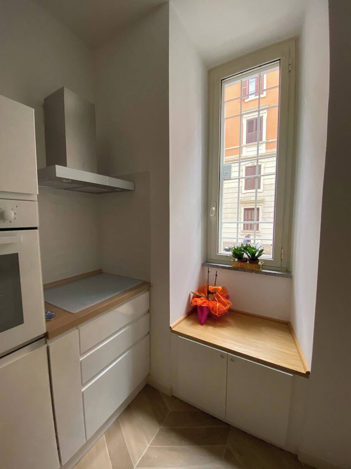 Une petite cuisine avec une fenêtre, un four encastré et un plan de travail en bois.
