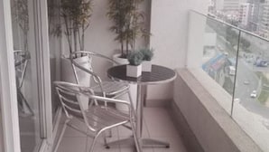 A small balcony with a round table and two chairs, two potted plants, and a view of the cityscape. - Departamento Centro de viña del mar (Vina del Mar)