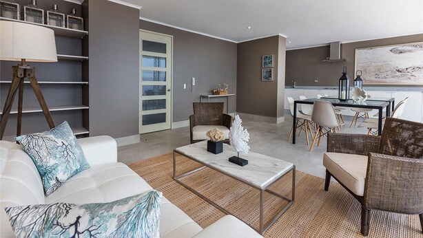 A modern living room with a white sofa, a coffee table, and a dining area with a table and chairs. - Departamento Centro de viña del mar (Vina del Mar)