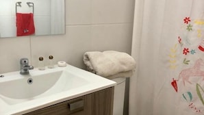 A bathroom with a white sink, wooden cabinet, and a toilet. - Departamento Centro de viña del mar (Vina del Mar)