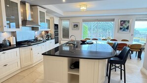 A modern kitchen with white cabinetry, a central island, and a dining area with chairs and a table. - Beautiful 7 BR Home Ring of Kerry - Beach -Golf nearby - Killarney 30 min.drive (Killarney)