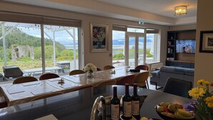 A dining area with a table set for six, a view of a mountainous landscape, and a television displaying a scene. - Beautiful 7 BR Home Ring of Kerry - Beach -Golf nearby - Killarney 30 min.drive (Killarney)