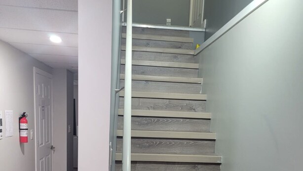 Una escalera de madera con barandilla metálica que conduce a un piso superior.