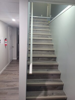 Eine Treppe mit Holzbodenstufen und einem Metallgeländer, die zu einer oberen Etage führt.