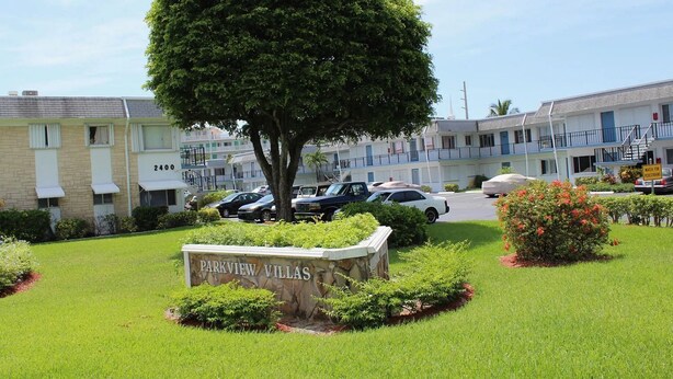 Señal de Parkview Villas con un césped cuidado y un árbol en primer plano.