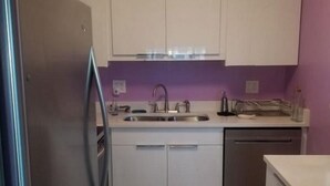 Una cocina compacta con refrigerador de acero inoxidable, pileta doble y lavavajillas.