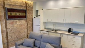 Ein kompakter Wohnbereich mit einer Couch, einer kleinen Küchenzeile und einer Ziegelwand.