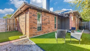 Een gelijkvloers gebouwd huis van baksteen met een overdekt terras, een kleine tuin en een zonnepaneel op het dak.