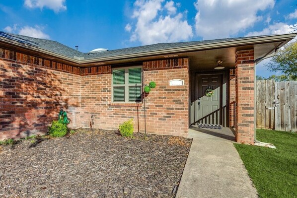 A brick house with a front porch, a mailbox, and a small garden area. - Cute Chic 2B 2B Duplex APT (Frisco)