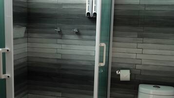 Une salle de bain équipée d’une douche, de toilettes et d’une poubelle.