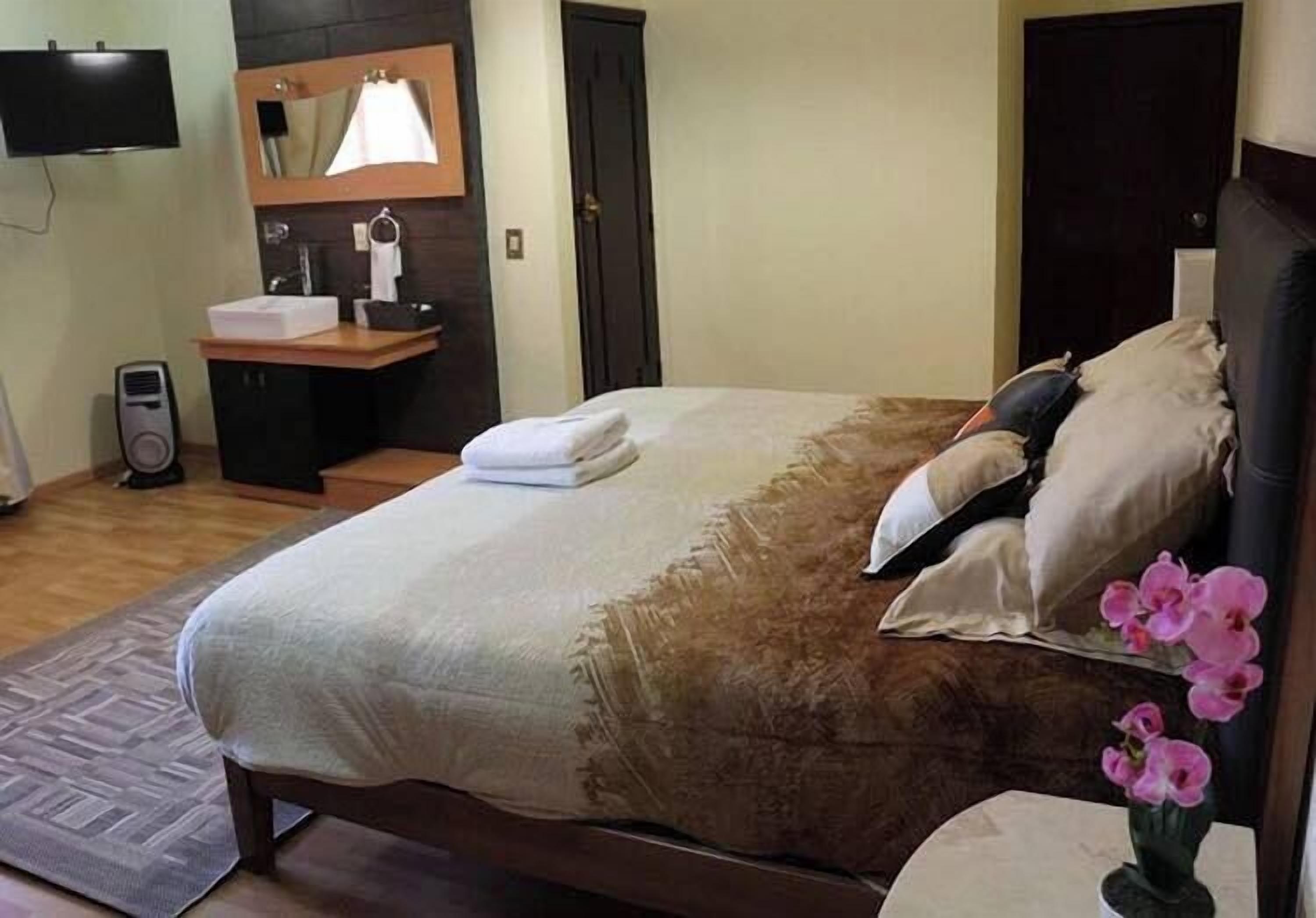 A neatly arranged bedroom with a bed, bedside table, and a small desk with a chair.