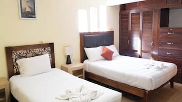 Two single beds with wooden headboards, a nightstand with a lamp, and a wardrobe with sliding doors.