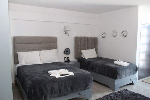 A modern bedroom with two beds, a bedside table, a lamp, and wall decorations.