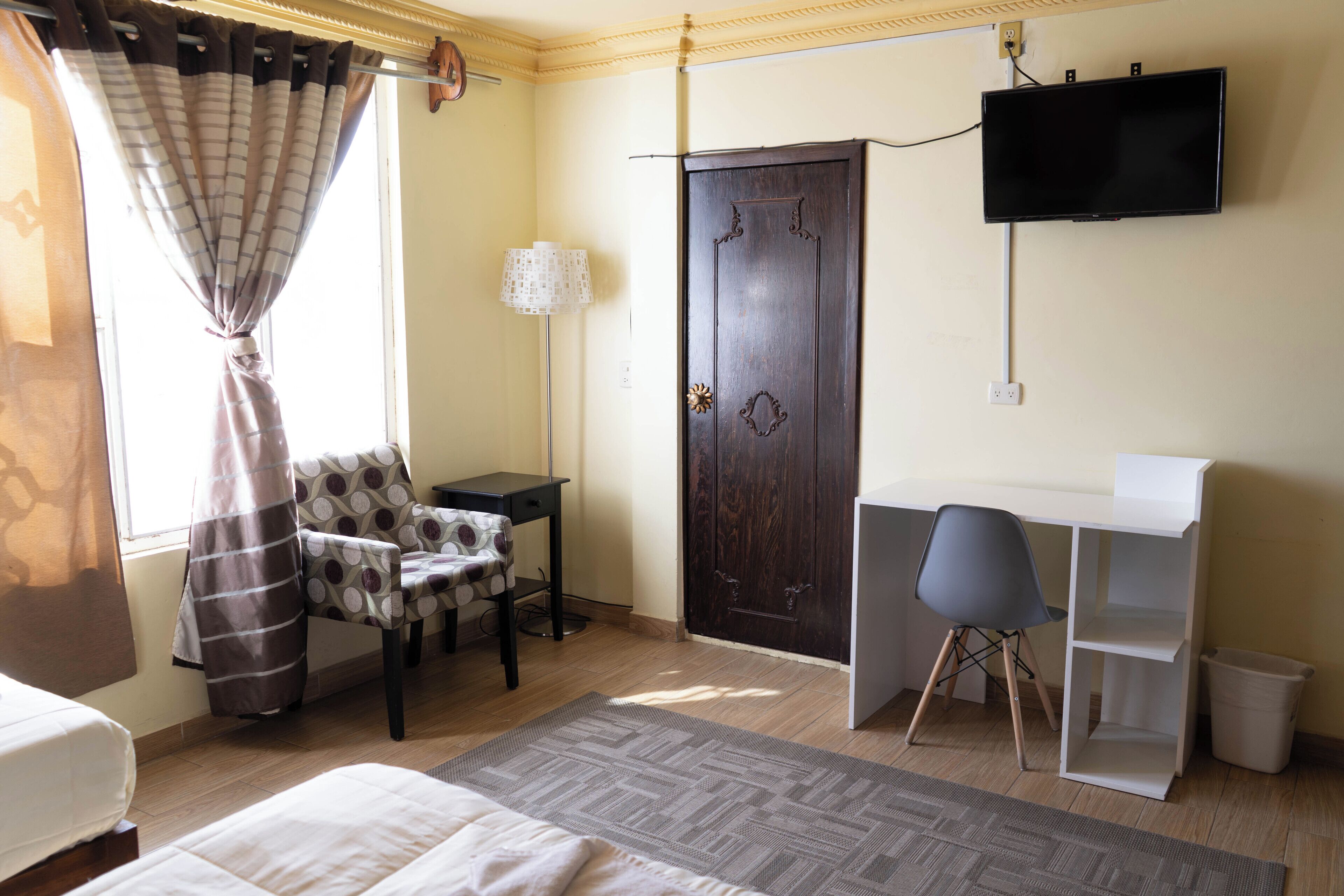 Un dormitorio con cama, escritorio, silla, televisor y armario.