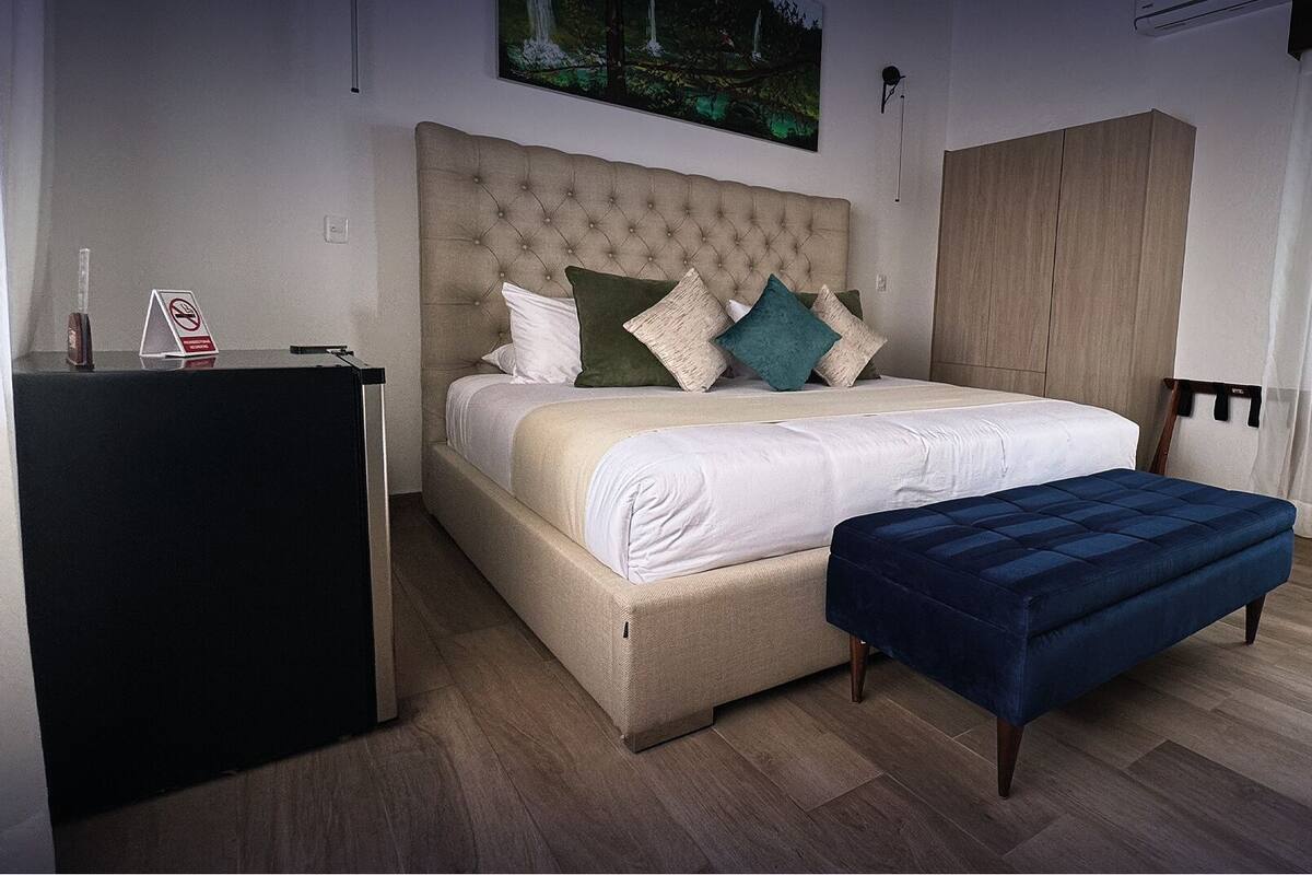 A bedroom with a large bed, a bedside table, a wardrobe, and a bench.