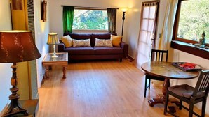 A cozy living room with a sofa, a small table, and a window with curtains.