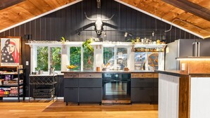 A modern kitchen with a wooden ceiling, a black countertop, and a large window. - As Unique as they come! (Intervale)