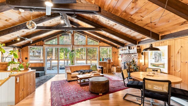 A spacious loft with a high ceiling, wooden beams, a large window, a cozy seating area, a dining table, and a kitchen area. - As Unique as they come! (Intervale)