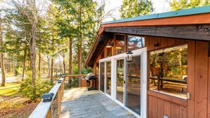 A wooden deck with a grill, glass doors, and a view of the surrounding forest. - As Unique as they come! (Intervale)