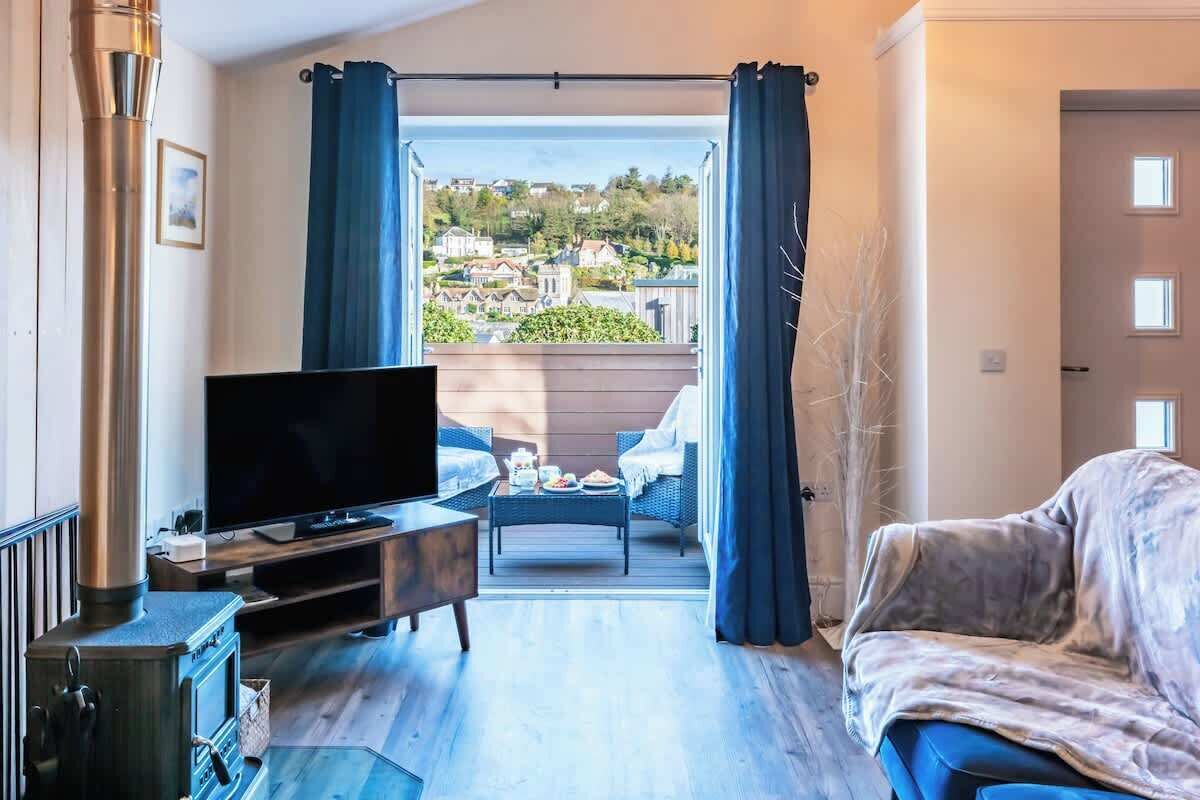 A living room with a TV, a sofa, a coffee table, and a view of a residential area through a window.