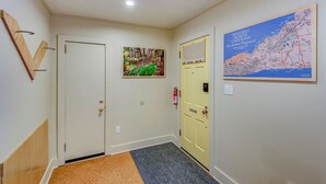 A hallway with a wooden door, a framed map, and a fire extinguisher.