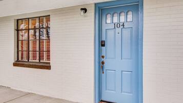 A white brick building with a blue door marked with the number 104.