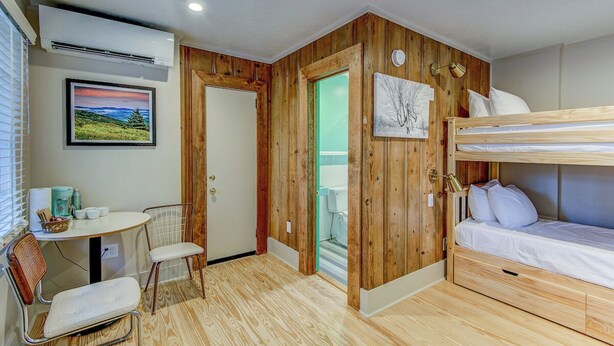 Habitació petita amb una llitera, una taula amb caires, un quadre al mur i un aparell d'aire condicionat.