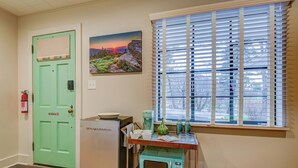 A compact kitchen with a green door, a small refrigerator, a microwave, and a window with blinds. - Historic Blue Ridge Tourist Court - Queen Plus (Boone)