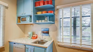 Una cocina compacta con refrigerador, microondas, pileta y armarios azules.