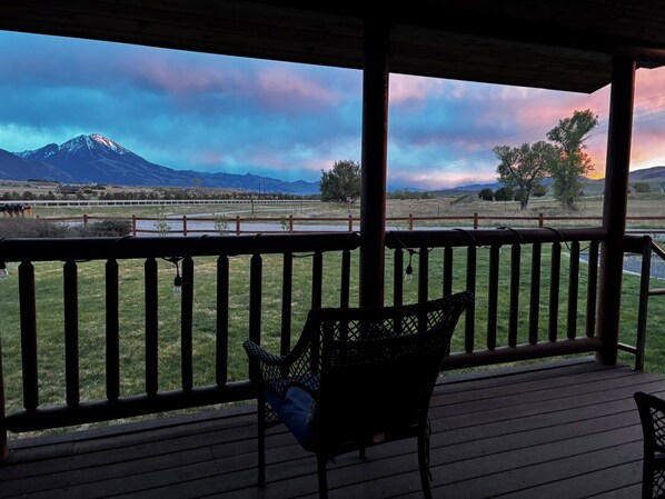 A covered outdoor area with a view of a mountain and a lake.