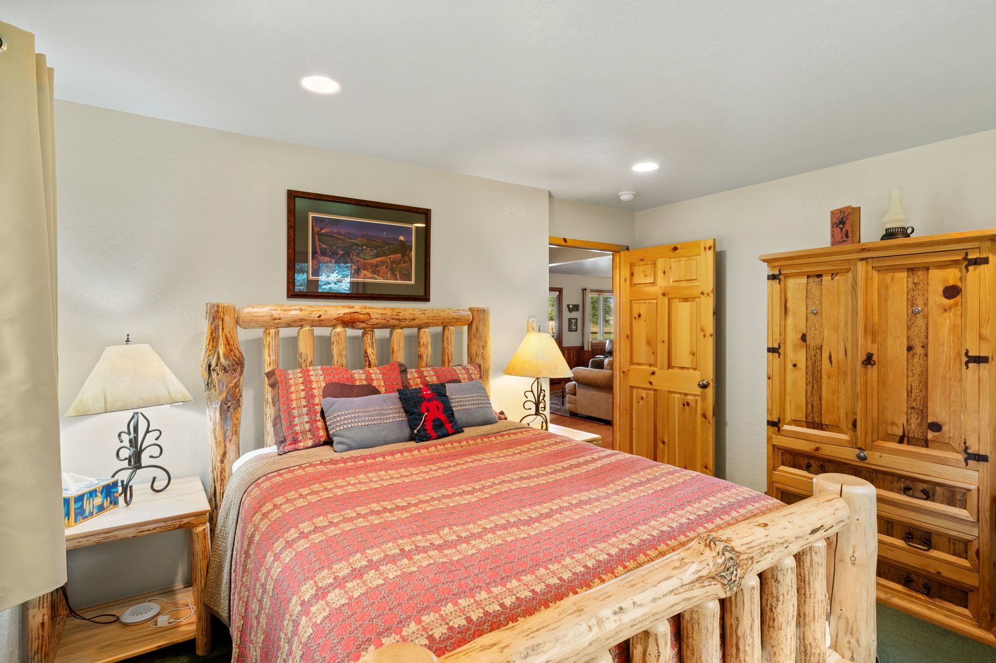 A bedroom with a wooden bed frame, a patterned bedspread, two bedside lamps, a nightstand, and a wardrobe.