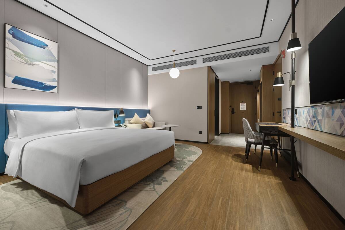 Une chambre d’hôtel moderne, dotée d’un grand lit, d’un bureau et d’une chaise.